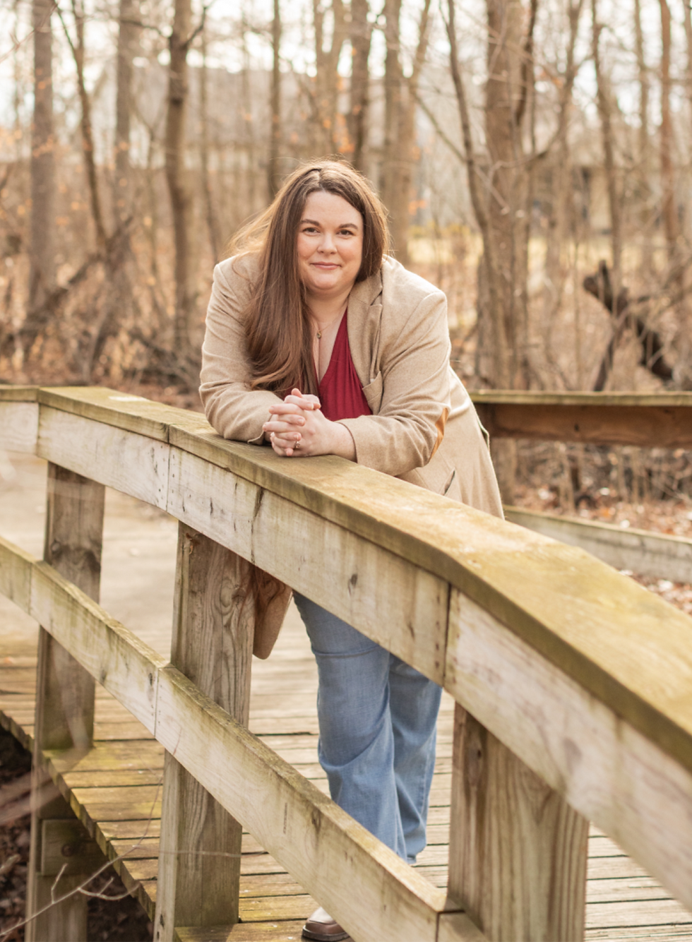 A woman leaning on the guardrail of a wooden bridge