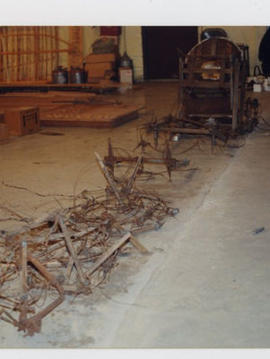 Parts of a Curtiss Jenny are laid out on a floor of a restoration shop