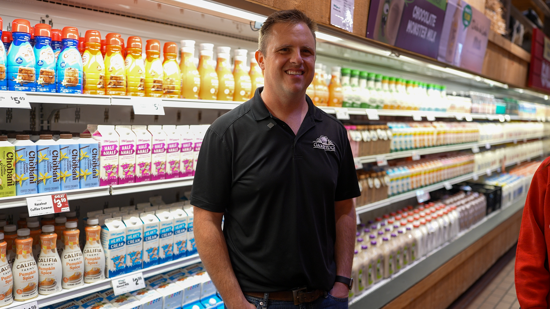 Oakridge Dairy team member standing in grocery dairy aisle with fresh milk and cream products on display