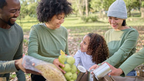 Multigenerational family volunteering outdoors, packing food donations for charity during the holidays 