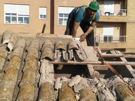 Un trabajador en un tejado con tejas rotas
