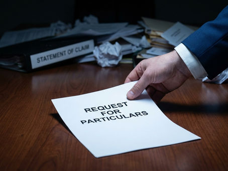 A close-up, slightly high-angle shot showing a person's hand in a blue suit jacket and white shirt cuff placing a white document titled "REQUEST FOR PARTICULARS" onto a polished wooden desk. In the background, slightly out of focus, is a cluttered desk with crumpled papers and a binder labeled "STATEMENT OF CLAIM." The lighting is dramatic and moody, highlighting the document in the foreground.