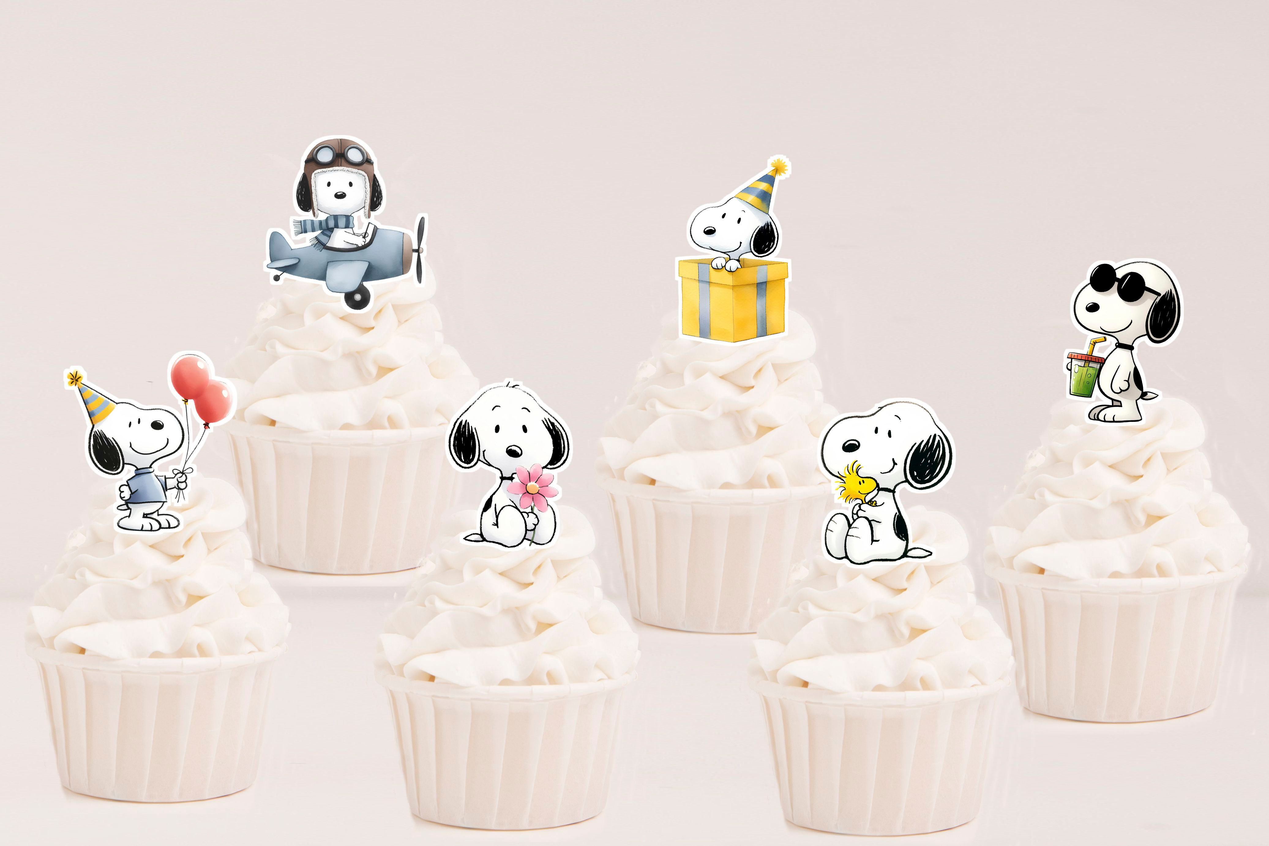 Toppers recortados Snoopy com avião, balões, presente, flores, óculos de sol e Woodstock sobre cupcakes.