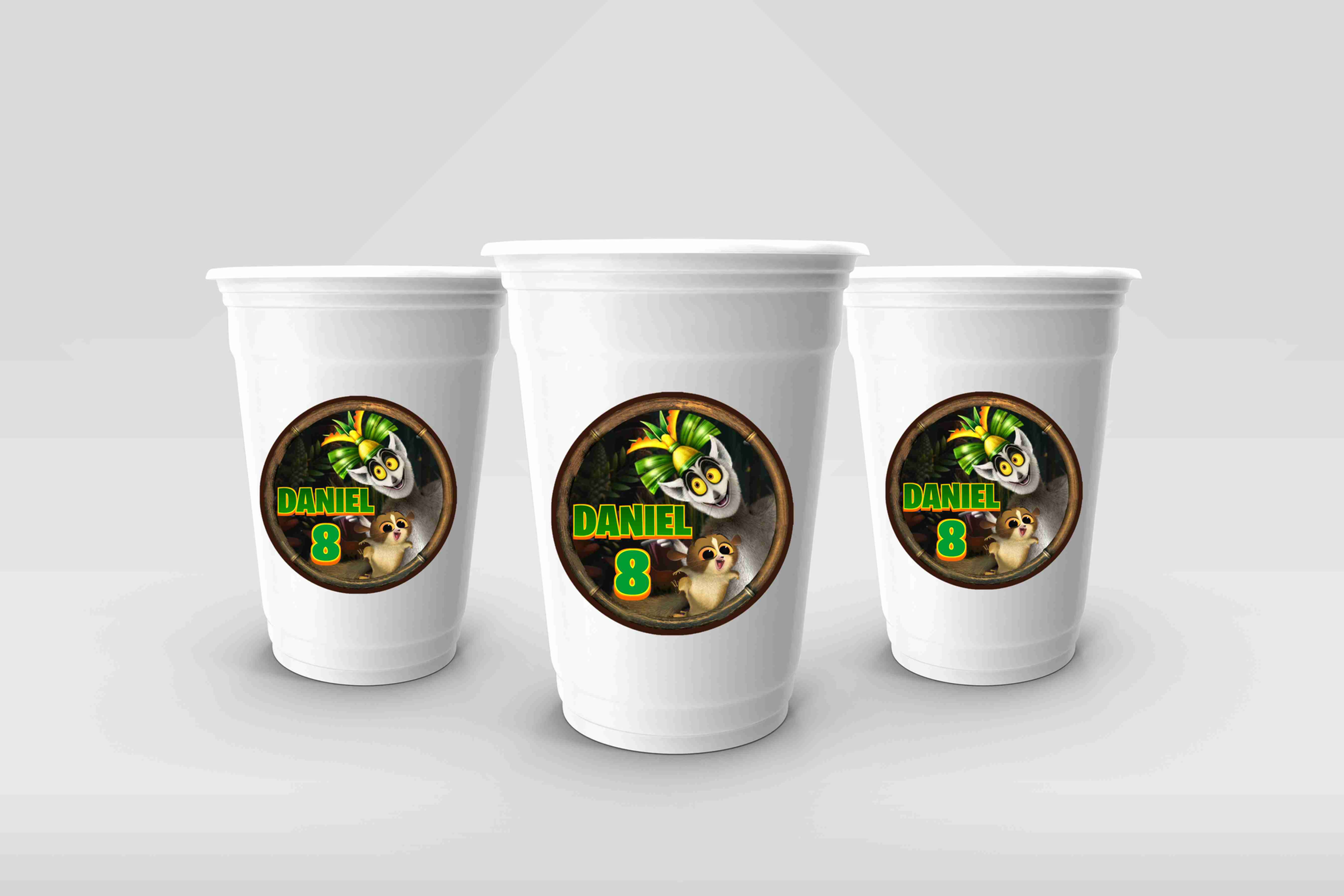 Copos descartáveis com autocolantes personalizados do tema Viva o Rei Juliano, com nome e idade, em cenário de selva divertid