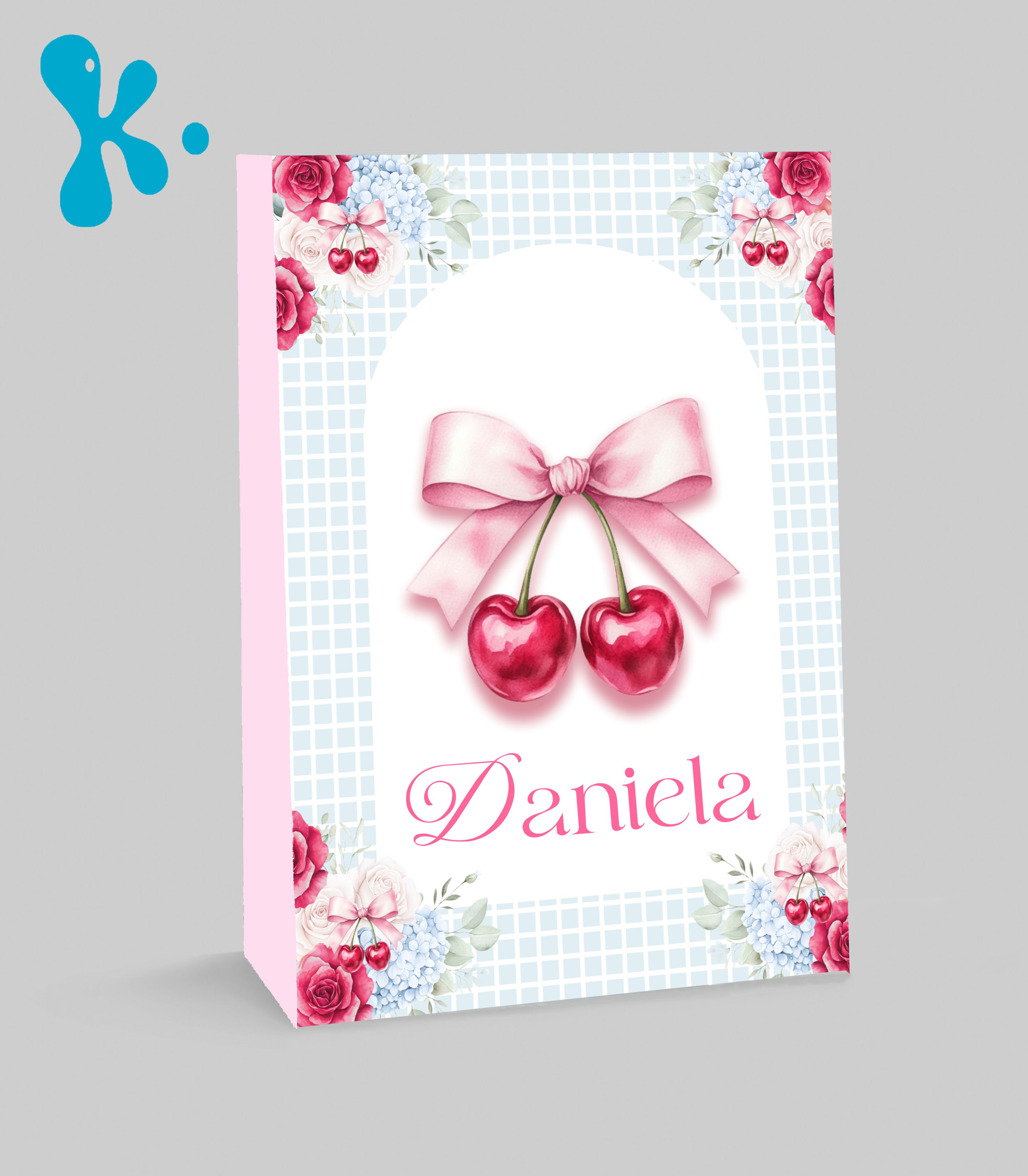 Saco lembrança personalizado cerejinhas com laço rosa, flores nos cantos e fundo azul quadriculado.