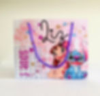 Sacolinha personalizada Lilo e Stitch em papel fotográfico, com fundo rosa, estrelas, flores, nome e idade da criança.
