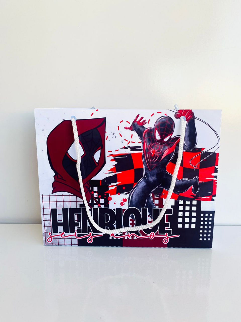 Sacolinha personalizada Spider-Man Miles Morales, com herói de fato preto e vermelho, cenário urbano, nome e idade da criança