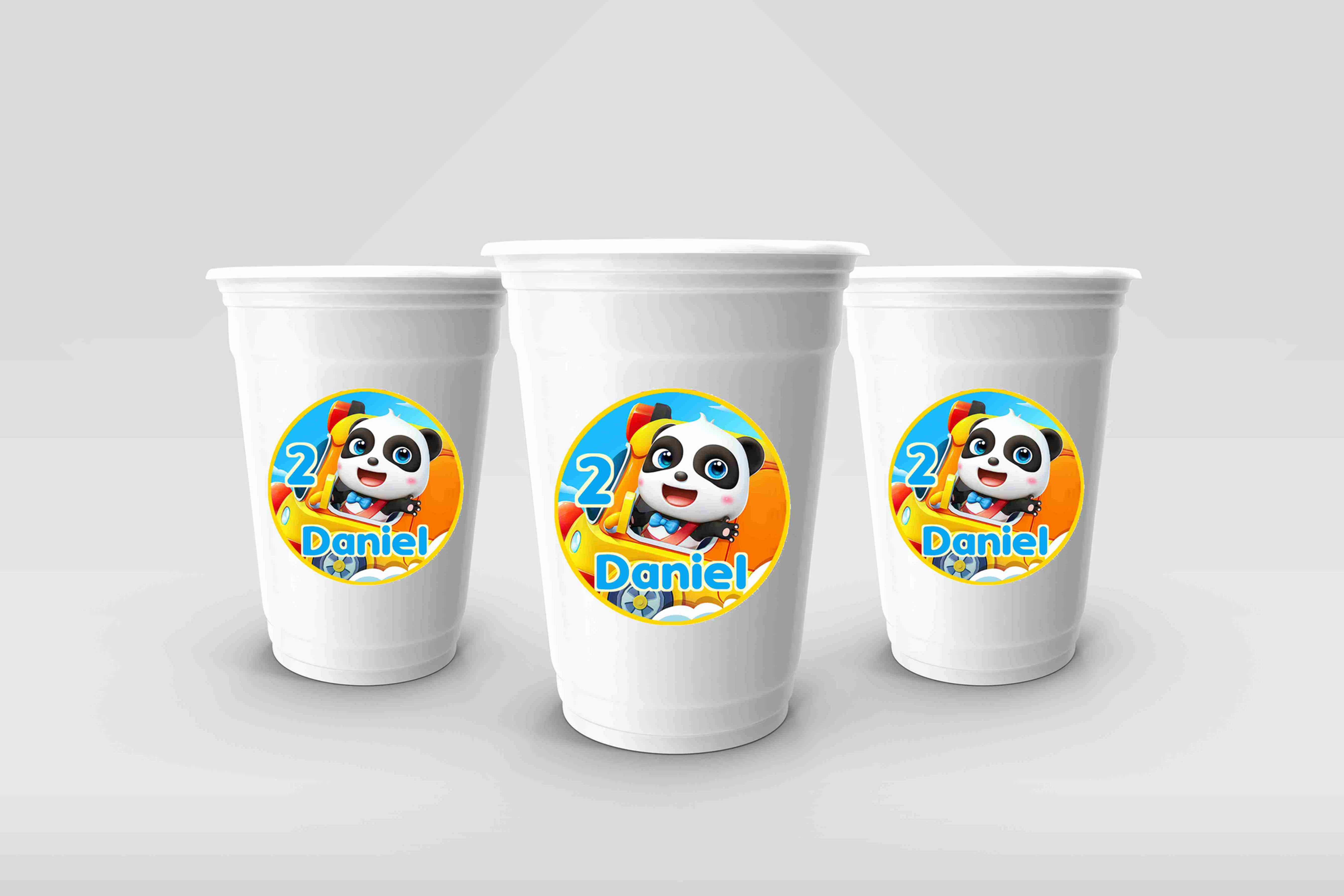 Autocolantes BabyBus personalizados aplicados em copos brancos com panda BabyBus colorido e nome da criança