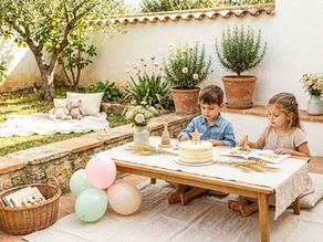 Festa infantil calma com decoração suave, mesa simples e crianças a brincar num ambiente tranquilo.