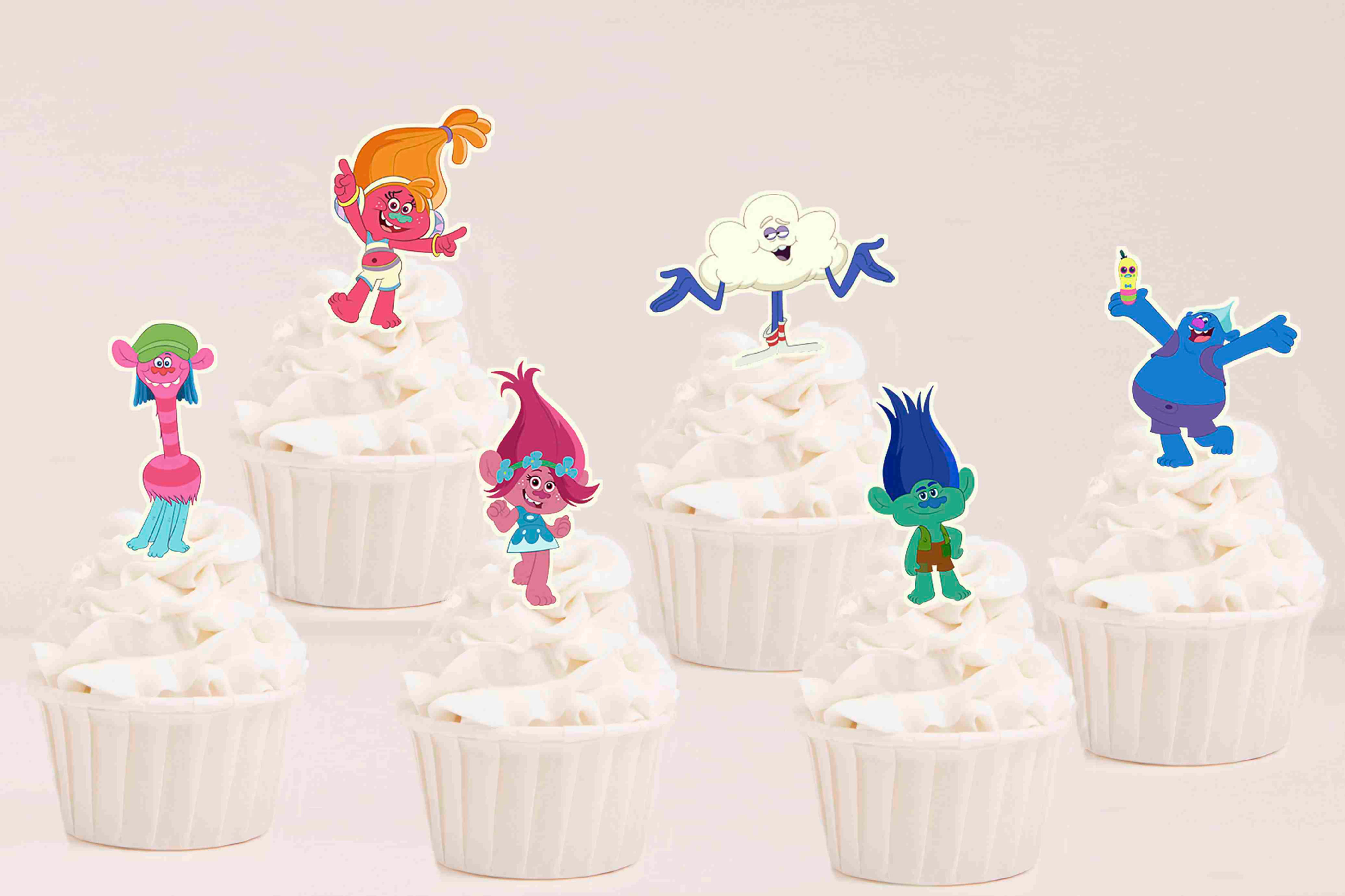 Toppers recortados Trolls com personagens coloridas aplicadas em cupcakes para festa infantil.