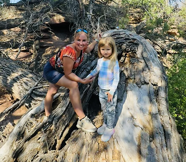 Woman and child smiling on a tree trunk