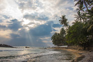 Sonnenstrahlen durch Wolken am Palmenstrand in Sri Lanka