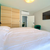 Confortevole camera da letto con un letto grande, armadio, dettagli verdi e TV.