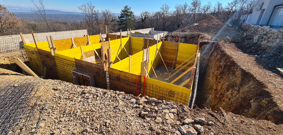 Yellow formwork in a house construction excavation, landscape in the background