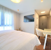 Confortevole camera da letto con letto, TV, tavolo e sedia. GALLERIA