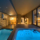 Interno con piscina e jacuzzi, arredato in stile moderno e con una bella illuminazione.