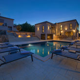 Villa di lusso con piscina, lettini prendisole e luci notturne, atmosfera accogliente.
