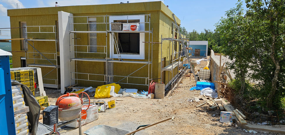 Casa in costruzione con finestra e impalcature, materiali da costruzione nelle vicinanze.