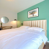 Accogliente camera da letto con letto, specchio e parete verde. GALLERIA.
