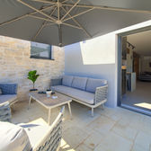 Comodi mobili per sedersi sulla terrazza esterna con ombrellone e vista.