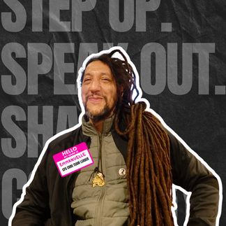 A photo of Emmanuelle, he is smiling. He has long dark dreadlocks and is wearing a sticker thats says "Hello my name is Emmanuelle. CFG Core Team Leader" 