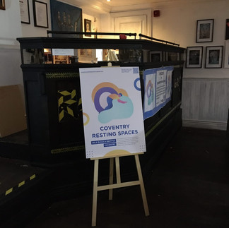 A photo of the Resting Spaces poster displayed on a wooden easel