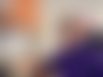 Ruth sitting at her desk, smiling with a headset on and purple Colostomy UK jumper