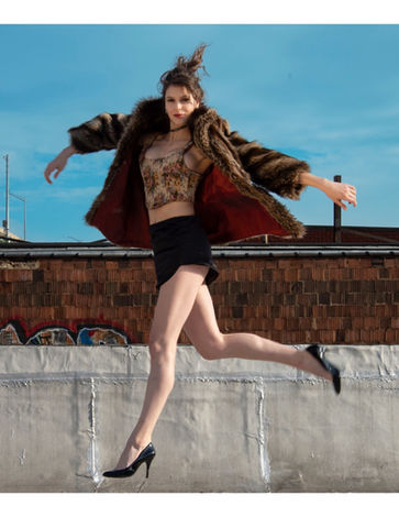 a woman wearing a fur coat and a crop top is jumping in the air