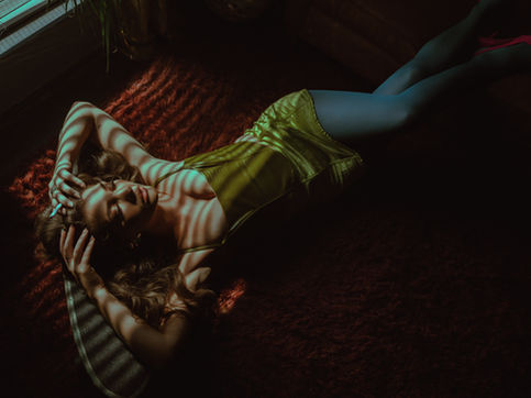 a vintage boudoir shoot of a woman laying on a shag rug in a green silk mini dress