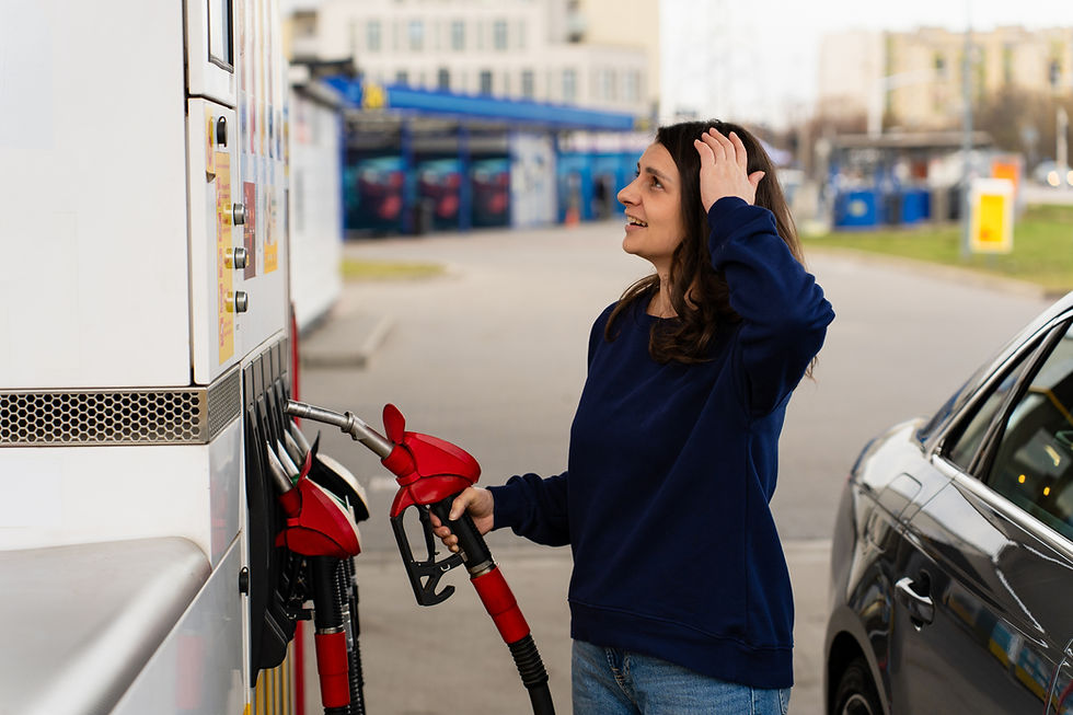 Shocked driver reacting to fuel price on pump while filling car. Woman looking surprised at fuel pump display while refueling car at gas station.