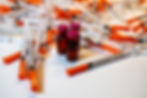 Cluster of peptide syringes and two small medicine vials with pink caps on a white surface, clinical and sterile scene