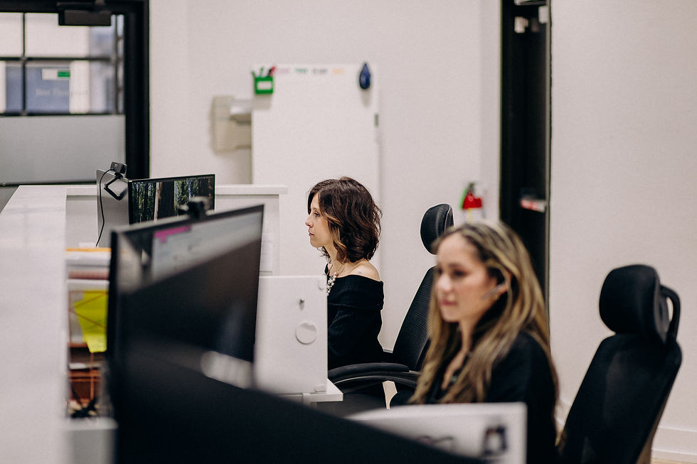 Two women focus on computer screens in a modern office with white walls. A small green sign is visible on the wall in the background. Arkansas Law Firm, Personal Injury Accident