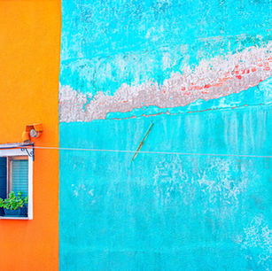 The side of the building that has a portion of it yellow, another orange, and a nother blue with a single windoa in the orange section