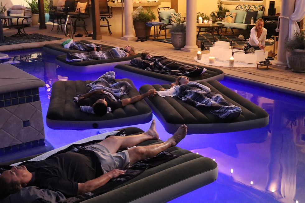 Floating sound bath participants relaxing in a pool listening to crystal singing bowls