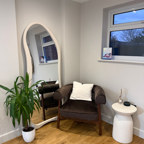 Stylish studio interior with wavy mirror, armchair, and plant