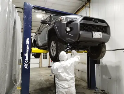 A man in a white suit working on a car