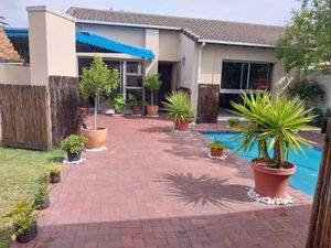 Friends enjoying a traditional South African braai at the outdoor BBQ area of Serenity Shores Backpackers, Bloubergstrand. Perfect for social evenings.