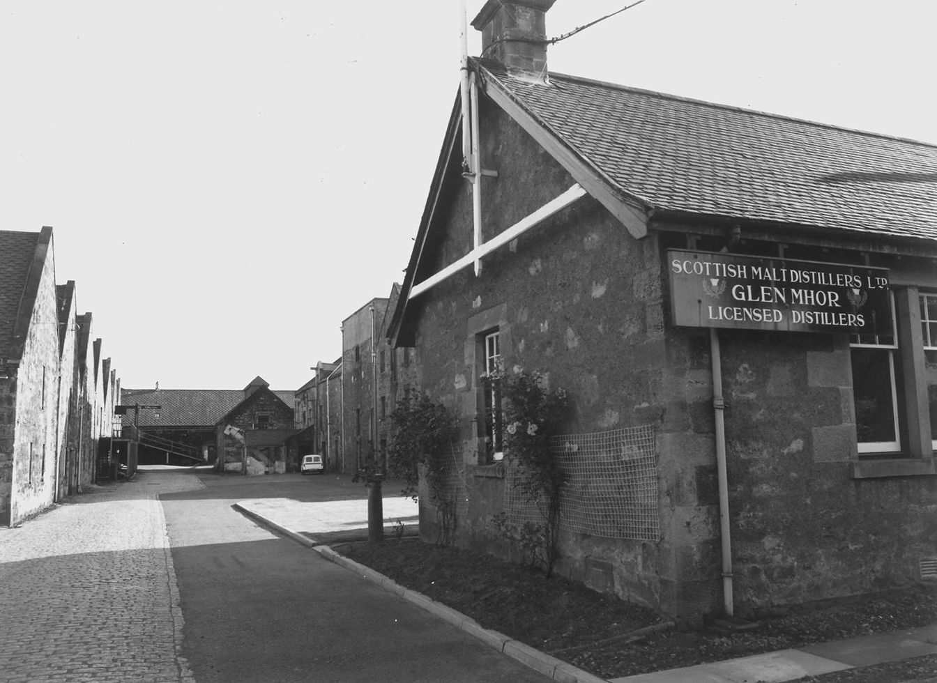 Black-and-white archival view of Glen Mhor’s courtyard with its Scottish Malt Distillers sign.