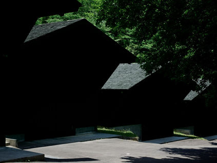 Dark timber distillery buildings beneath green trees at Osuzuyama in Miyazaki.