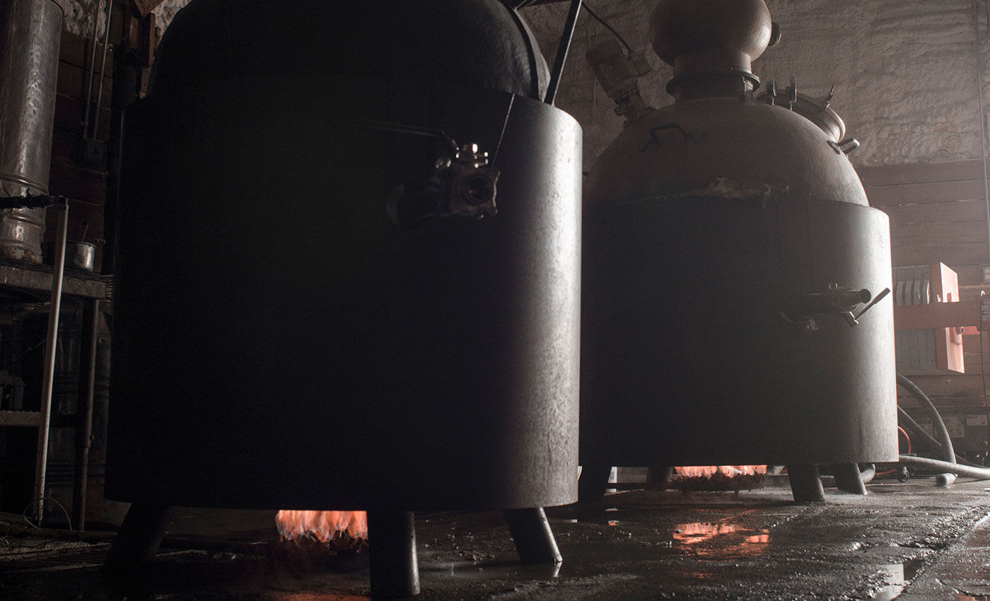 Historic Coppersea direct-fired stills with flames beneath the vessels