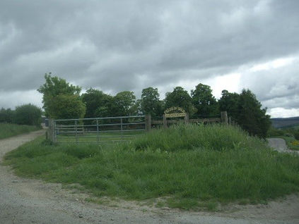 The signed entrance to Auchorachan farm, with a gate, fields and hills, photographed in June 2009