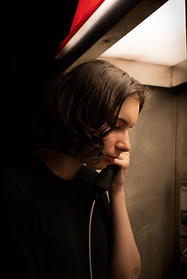 Creative portrait of person in phone booth red lighting dramatic lighting, moody portrait