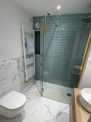 A beautiful bathroom with marble tiles and brushed brass walk in shower glass. 