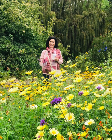Tour guest among the vivid yellow and orange autumn flower borders at Hidcote Manor Gardens, Cotswolds, in October