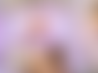 Bride in ornate attire reclines on a gold-trimmed sofa under a floral arch and chandelier, with white drapes and flowers adorning the setting.