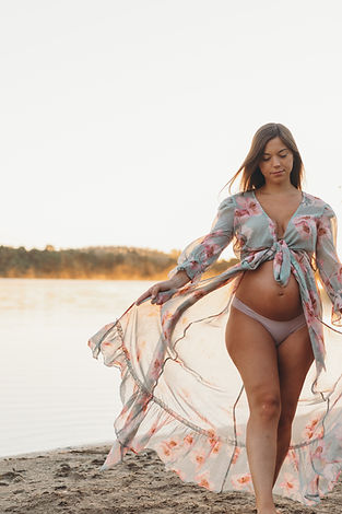 Pregnant mom opens up her floral wrap while she walks to show her bare belly