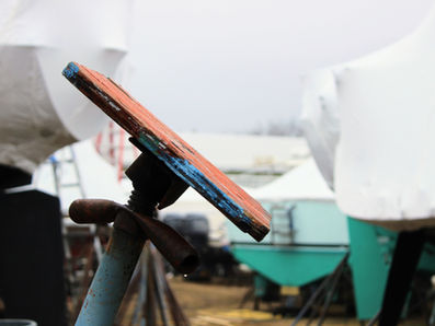 Boat stand in a winter storage yard with shrink-wrapped vessels in the background