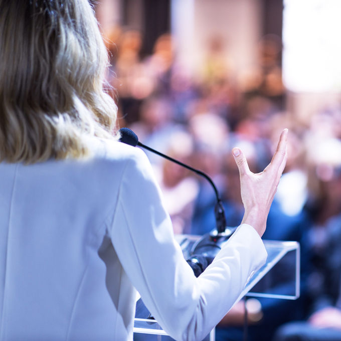 Speaker at podium addressing a large audience
