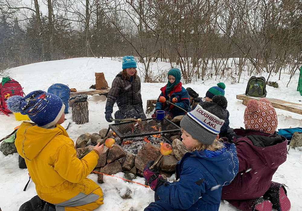 Children roasting apples around a campfire