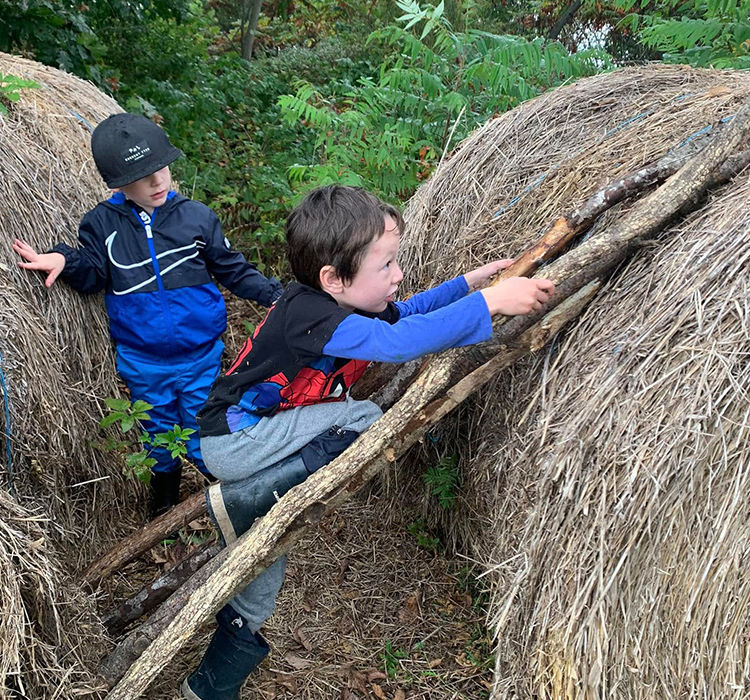 Kids climbing on haybales by using sticks